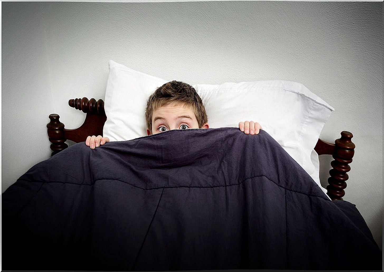 boy lying in bed waking up scared